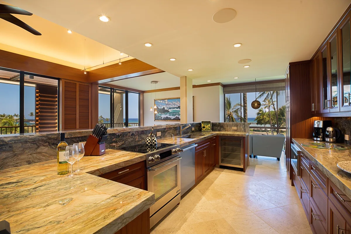 Una cocina amplia con encimeras de piedra, gabinetes de madera y grandes ventanas.