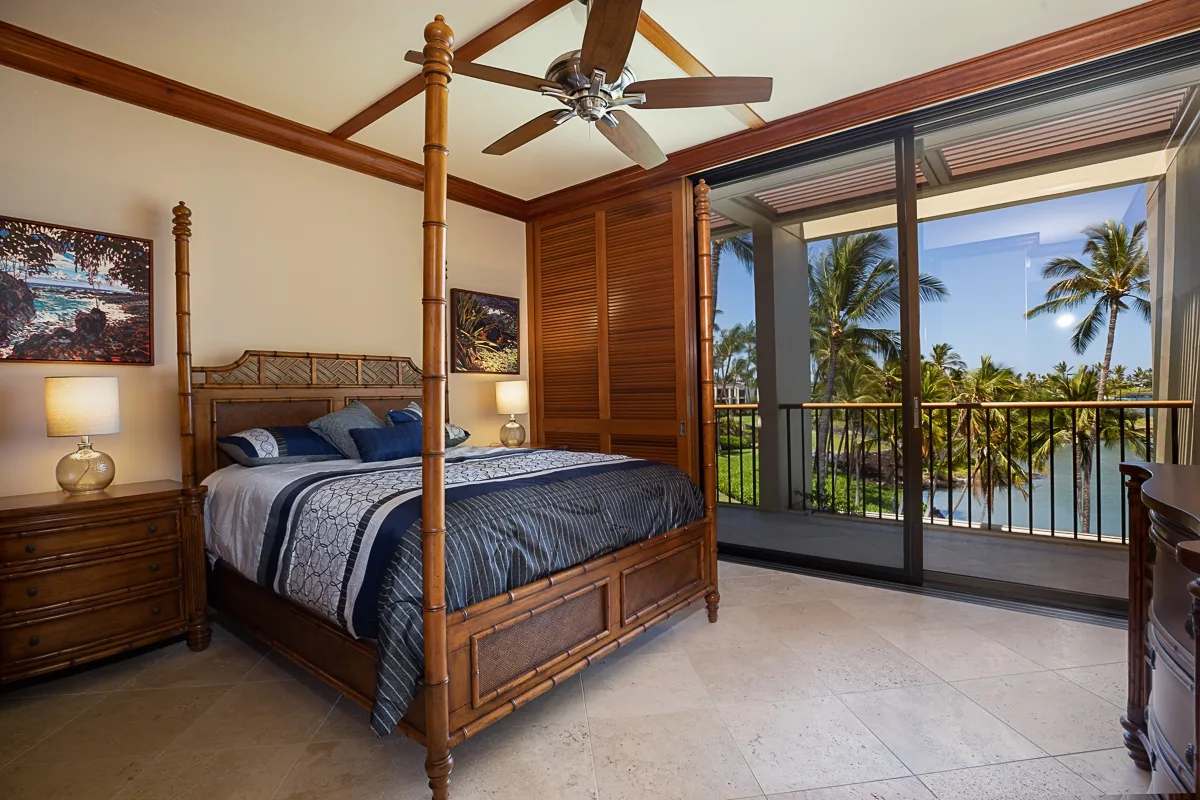 Un dormitorio con una cama de madera junto a puertas corredizas de vidrio que dan a un balcón.