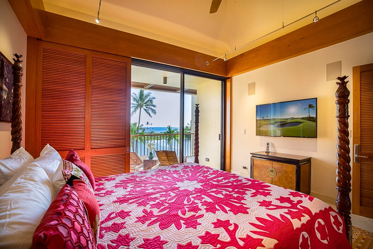Un dormitorio con una cama cubierta con una colcha floral llamativa y una puerta corrediza de vidrio.