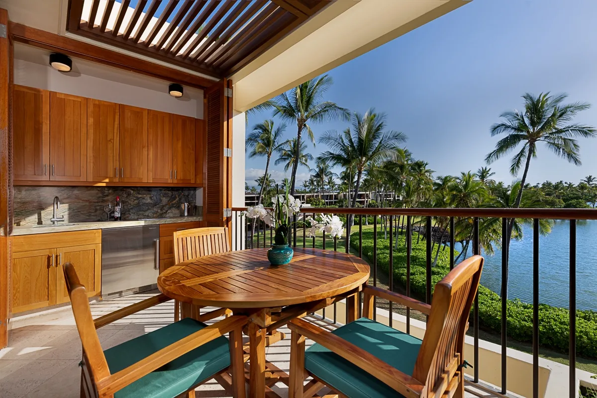 Un comedor en el balcón da a palmeras y al agua.