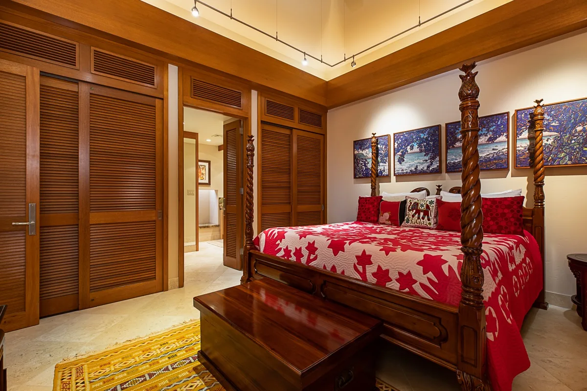 Un dormitorio con una cama roja estampada y muebles de madera oscura.