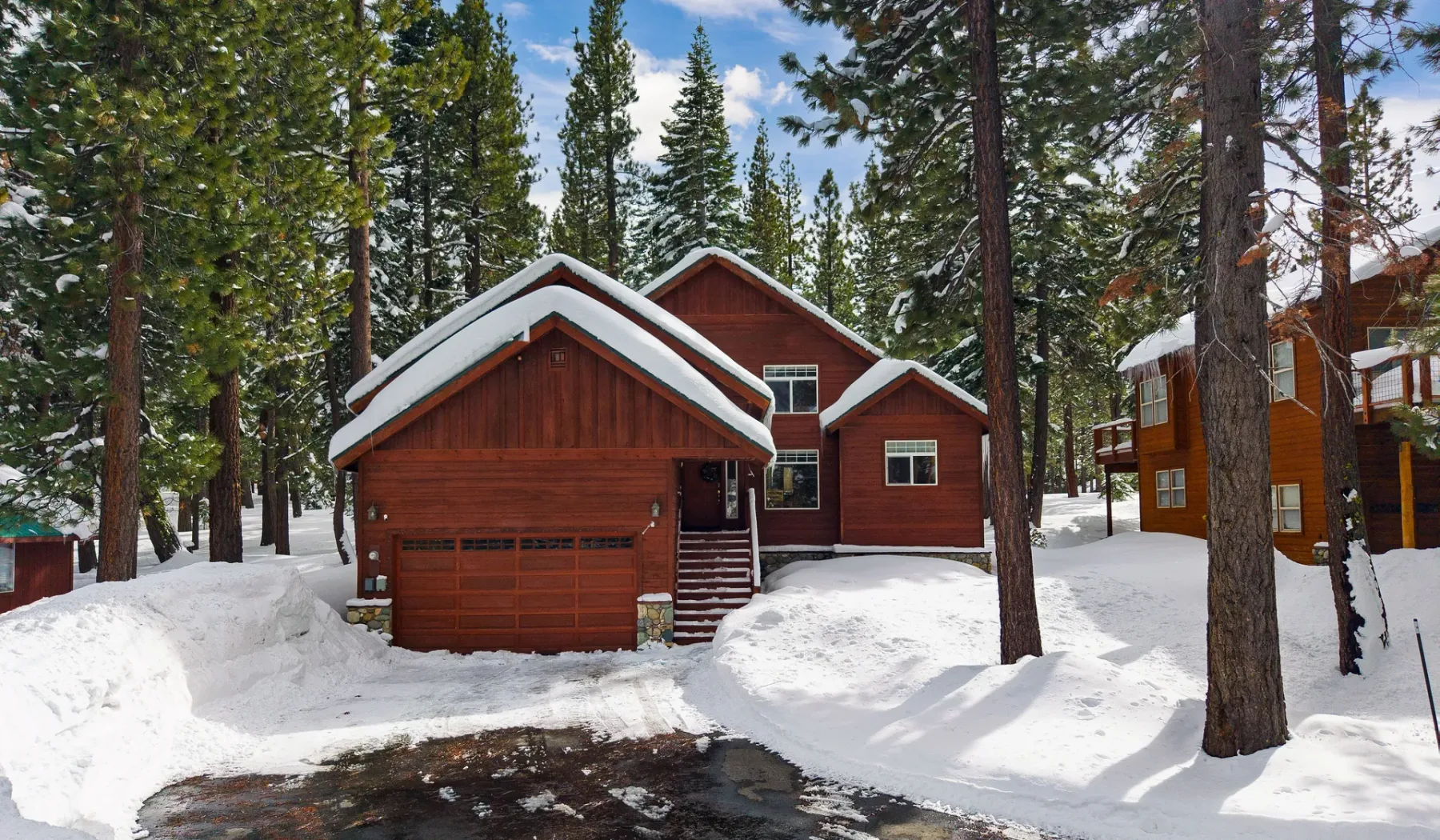 Cabañas de madera roja están entre árboles cubiertos de nieve.