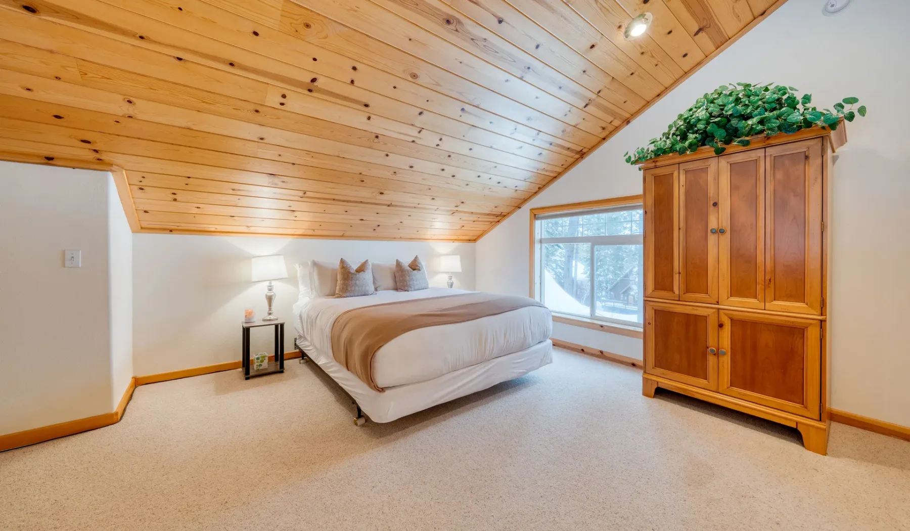 Un dormitorio con una cama bajo un techo inclinado revestido de madera.