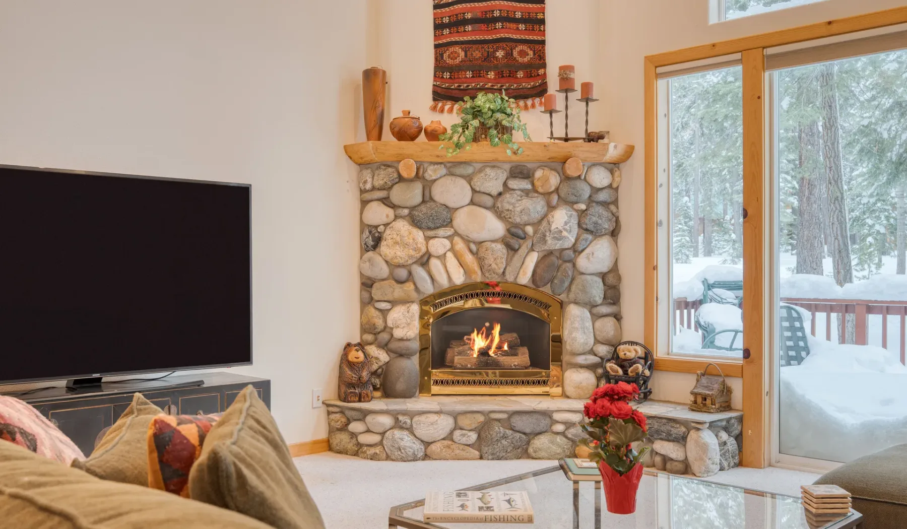 Una sala de estar con chimenea de piedra, televisor y asientos.