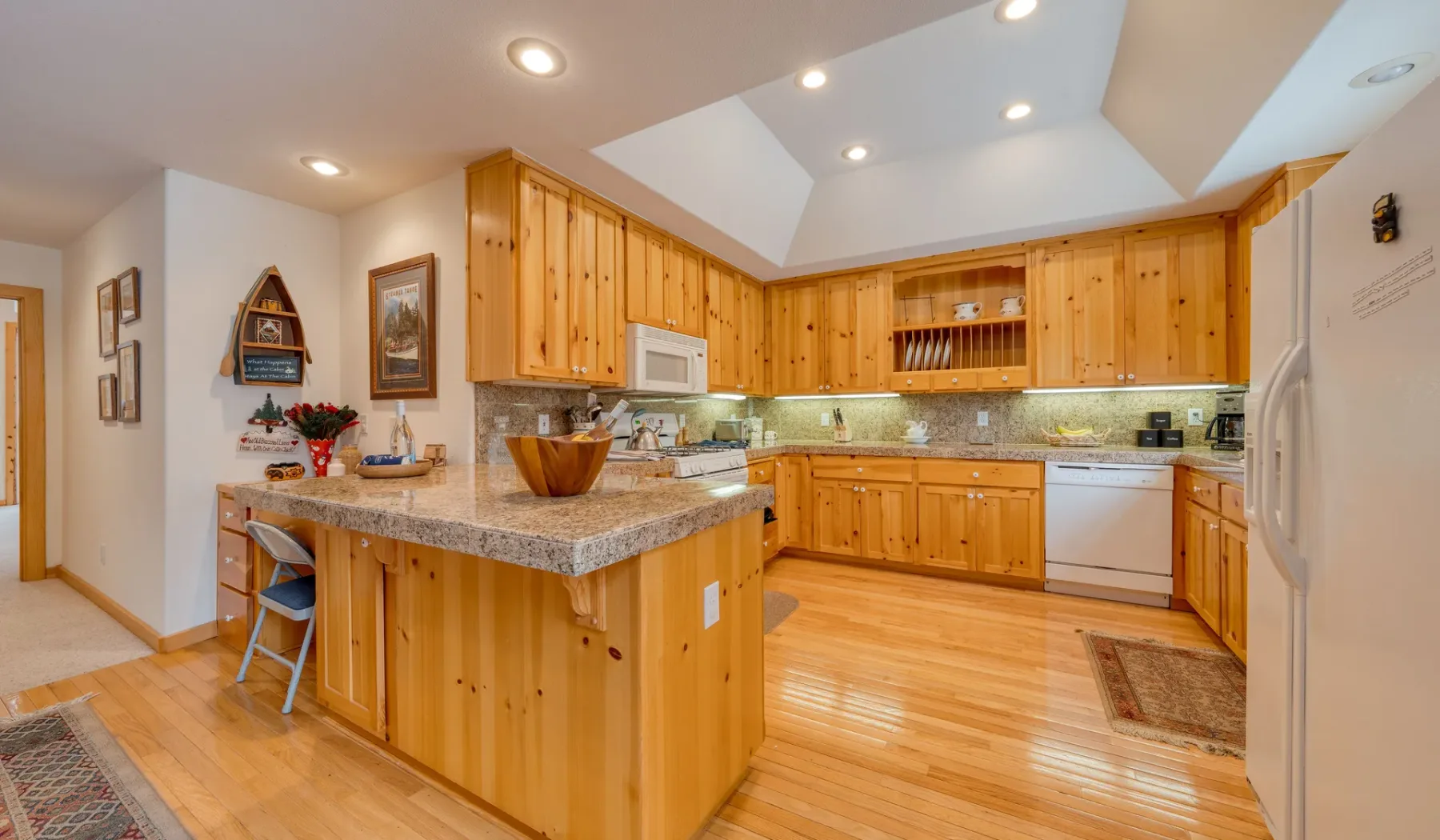 Una cocina con gabinetes de madera, una isla central y piso de madera clara.