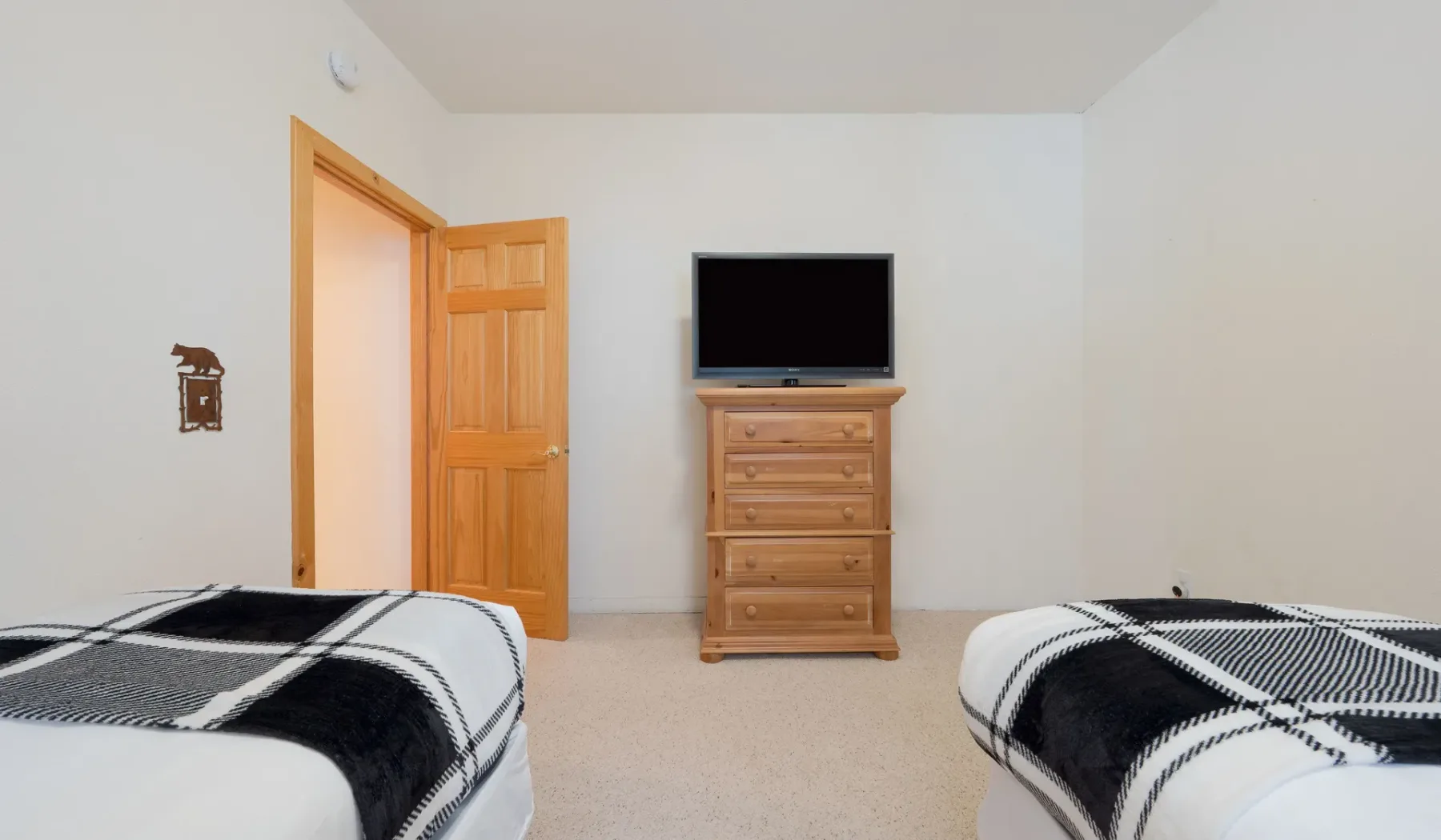 Un dormitorio con dos camas, una cómoda de madera y un televisor.
