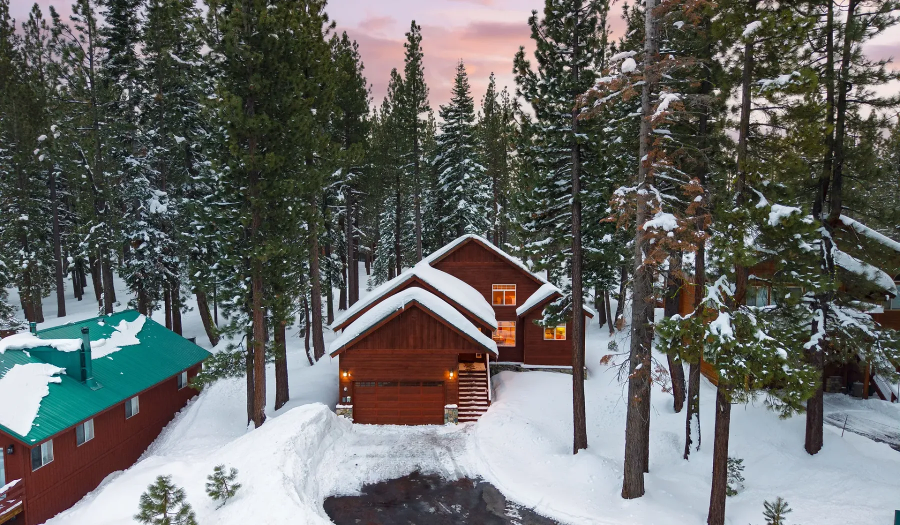 Una cabaña de madera está entre pinos cubiertos de nieve.