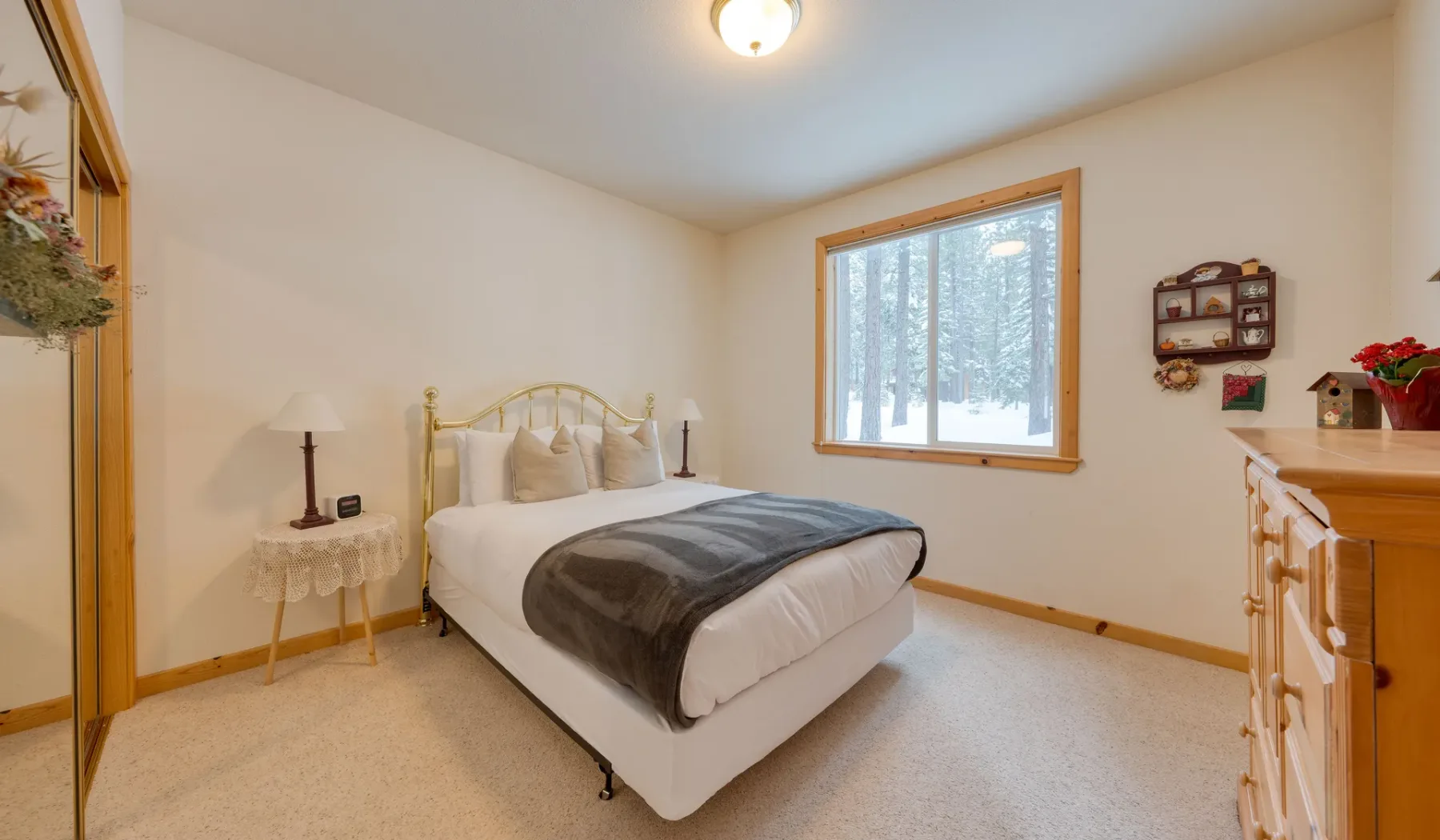 Un dormitorio con una cama junto a una ventana con vista a árboles nevados.