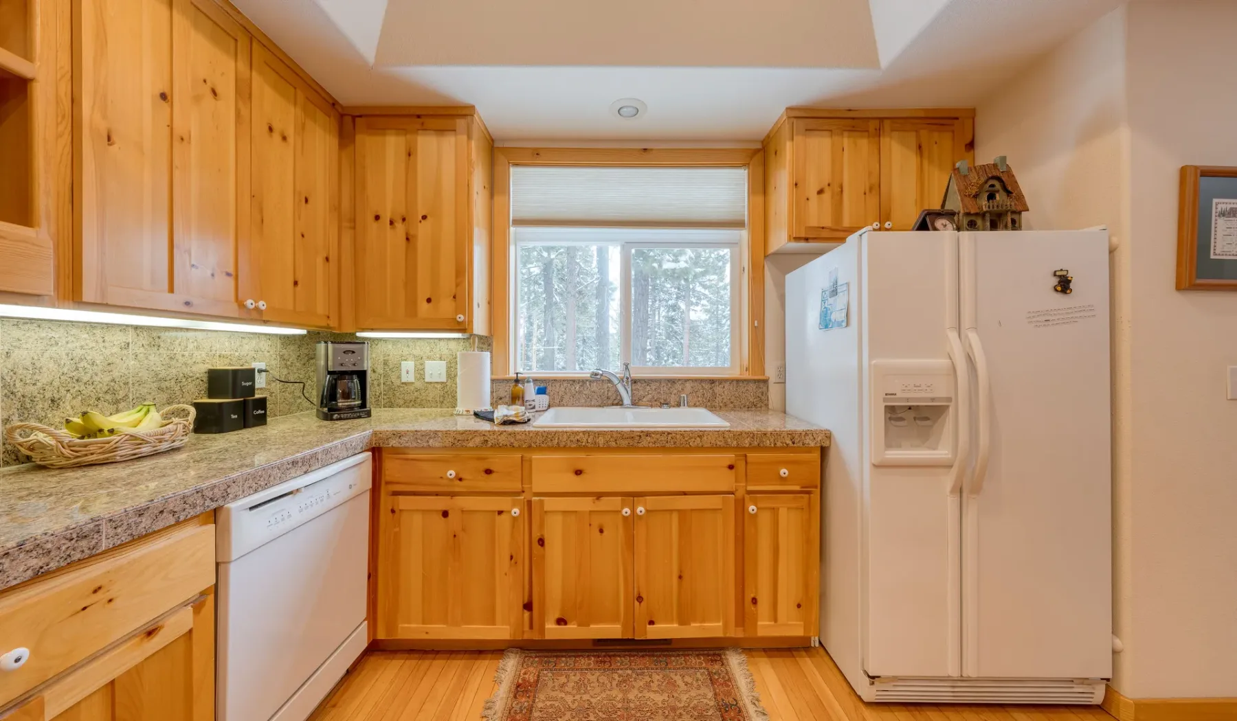 Una cocina con gabinetes de madera, una encimera y una ventana sobre el fregadero.