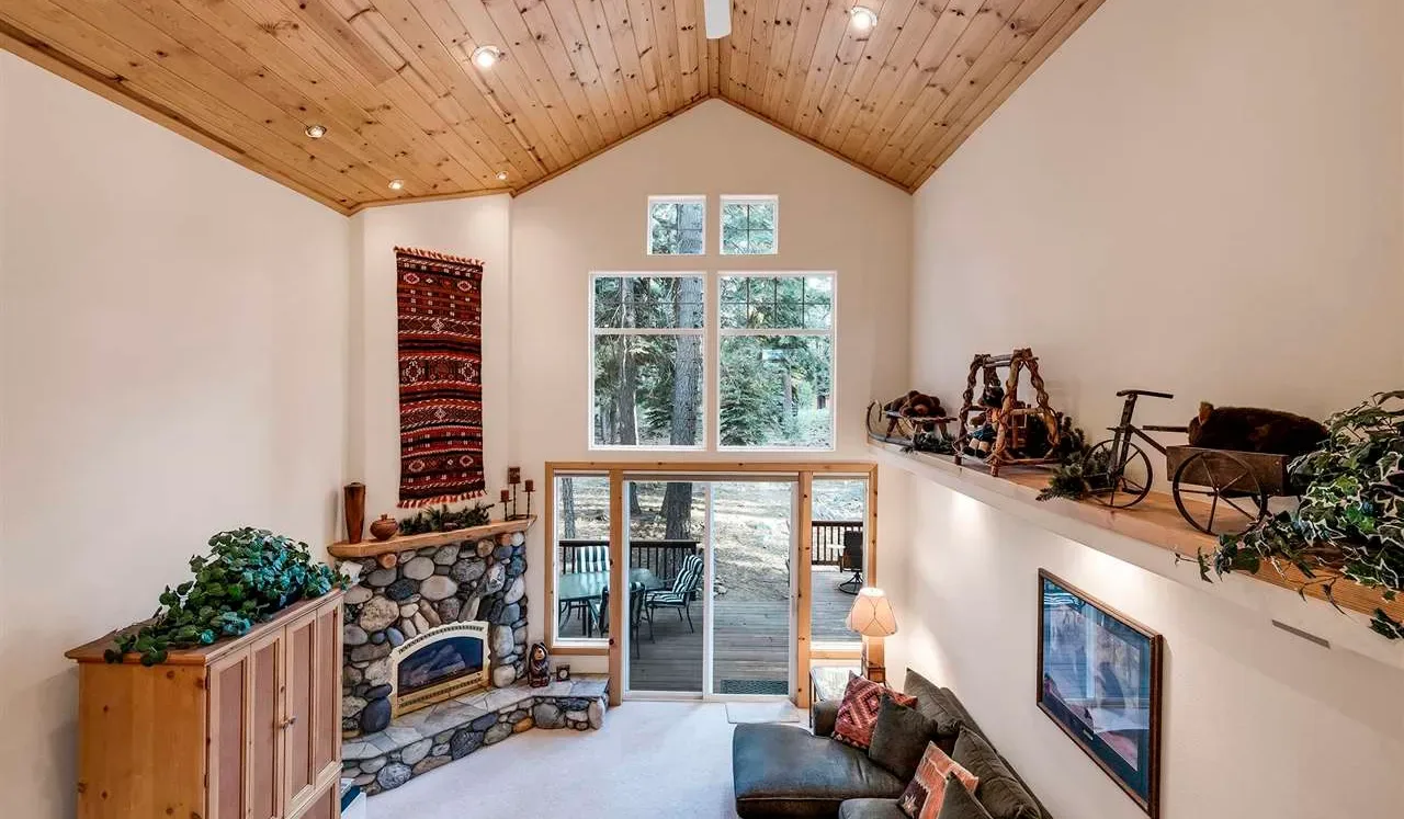 Una sala luminosa tiene techo abovedado de madera y ventanas grandes.