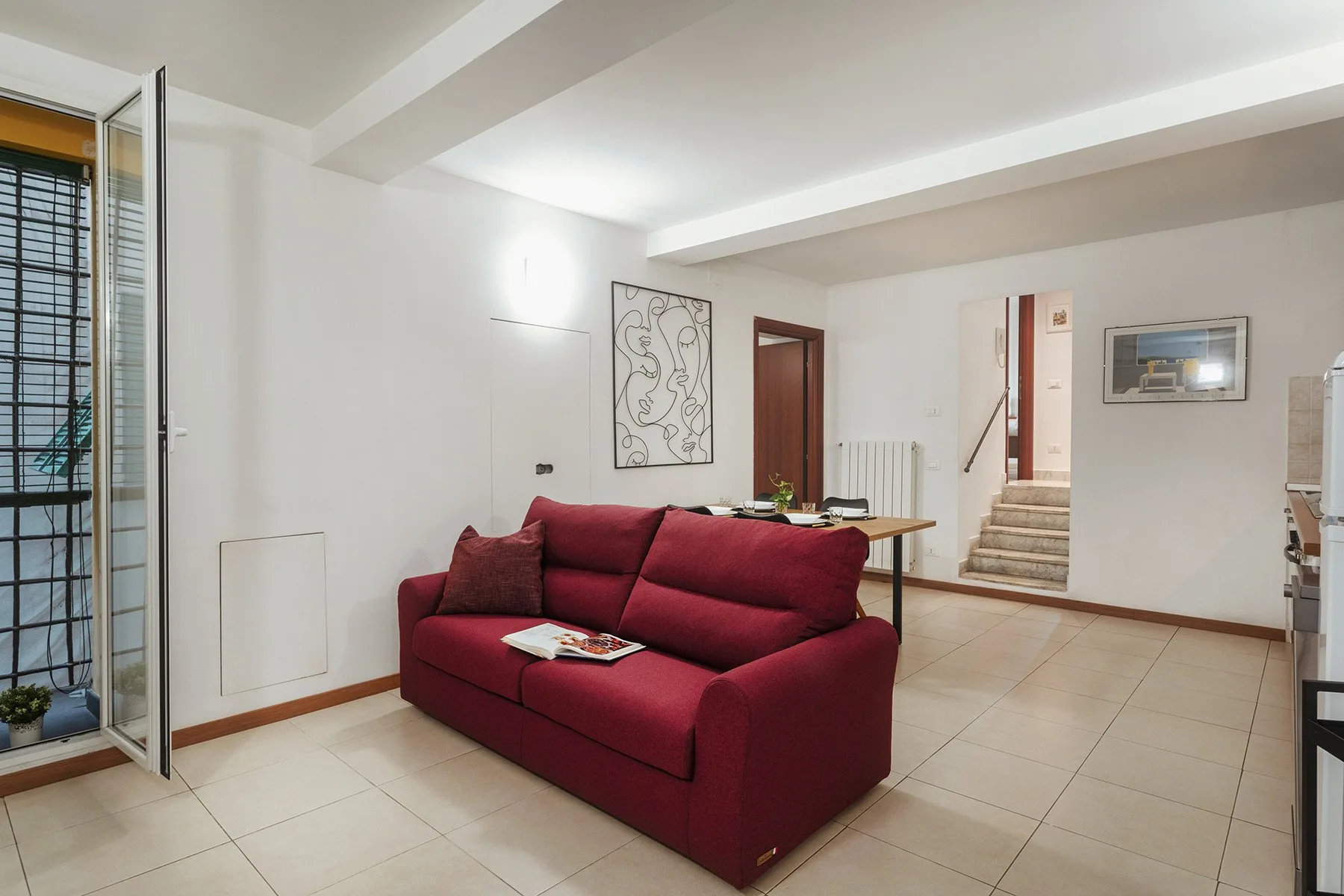 Una sala luminosa con asientos color burdeos y una mesa de comedor.