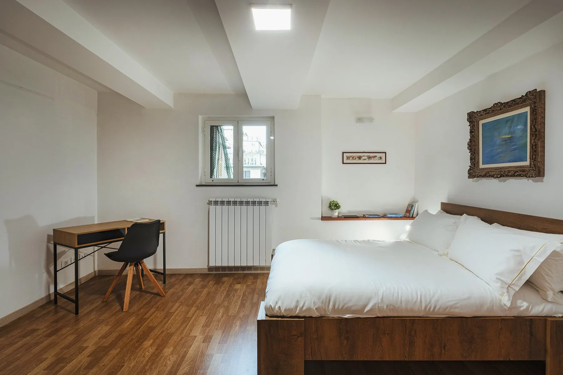 Un dormitorio con una cama grande, un escritorio pequeño y una ventana.