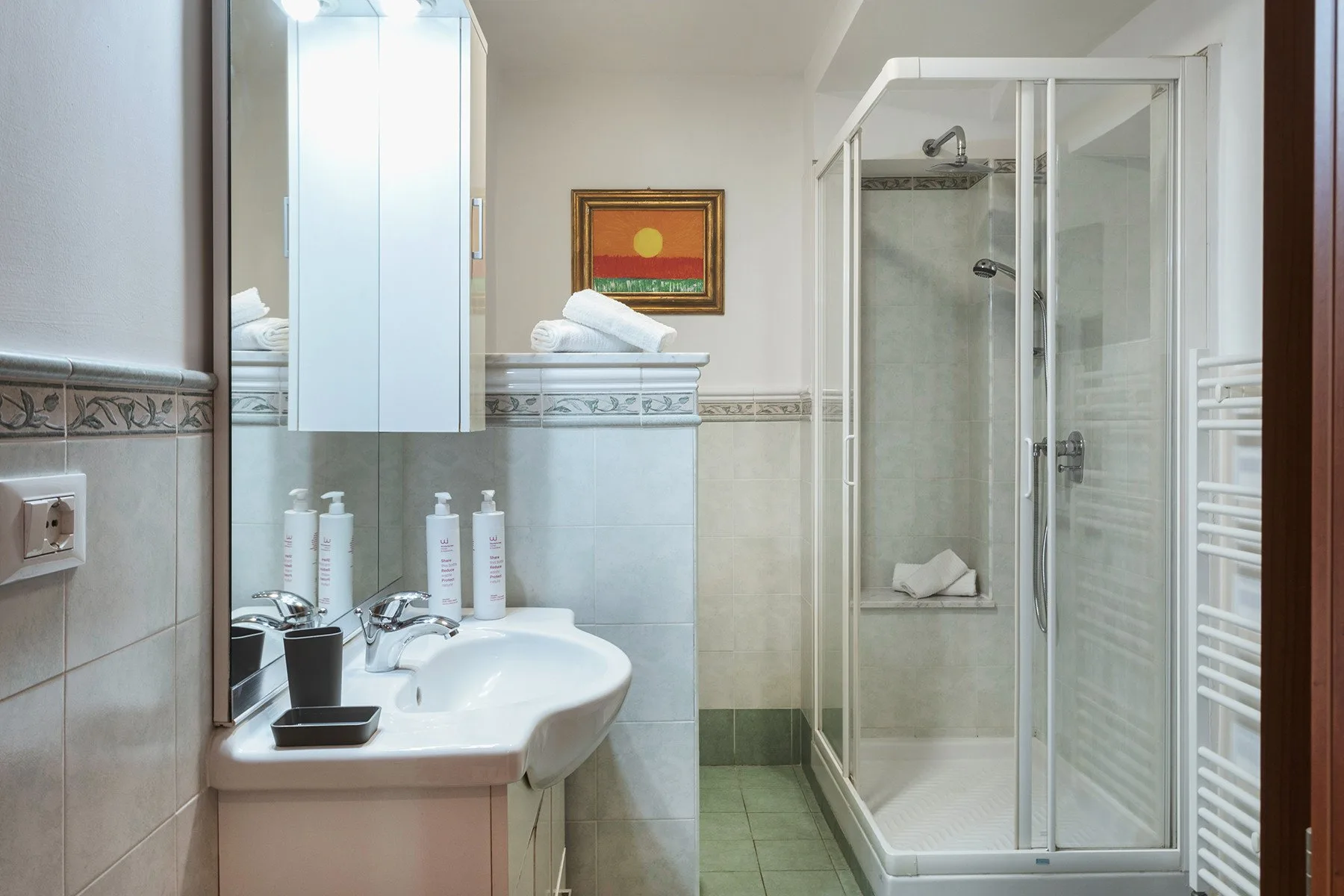 Un baño alicatado con lavabo y ducha de cristal.