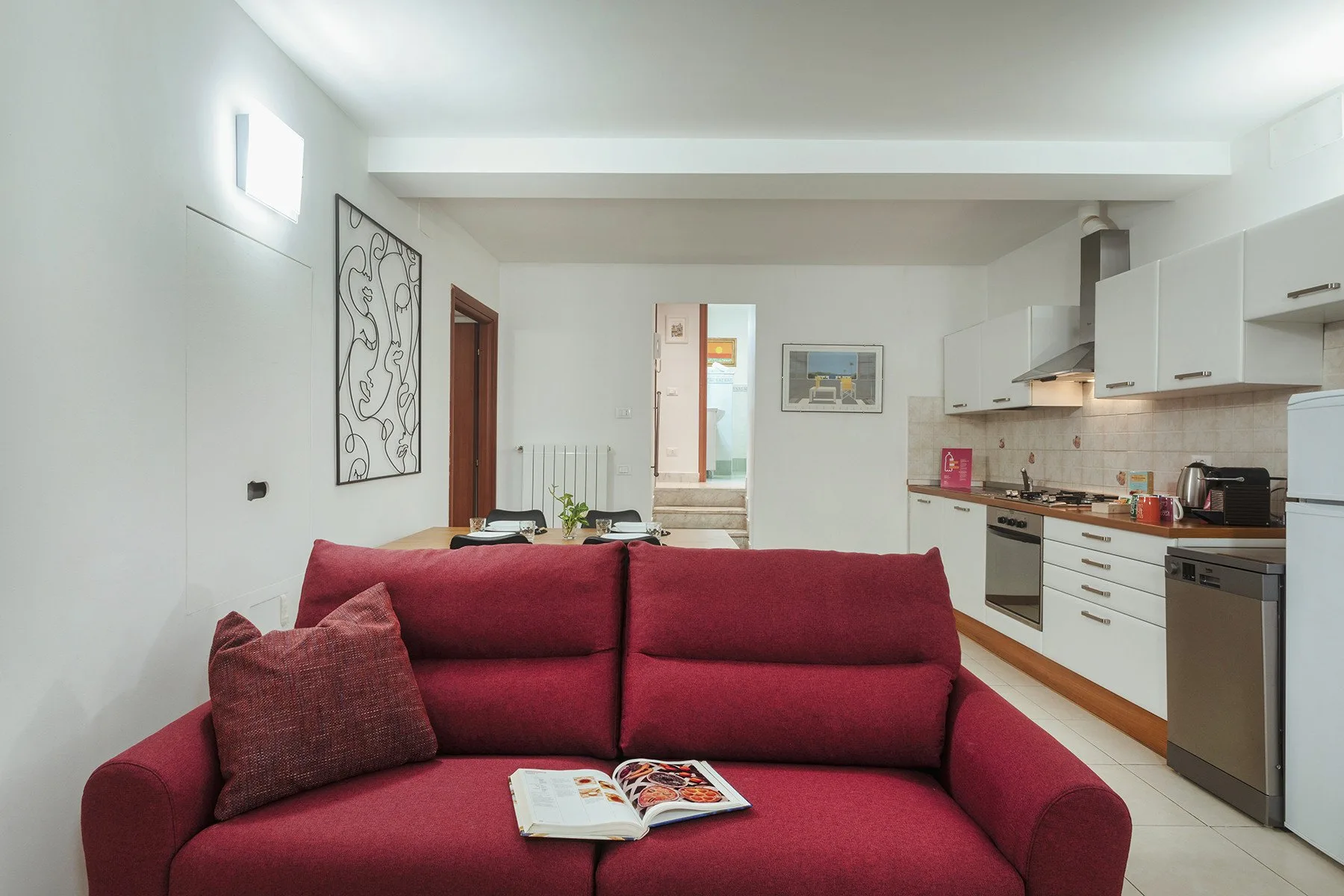 Una sala de estar con asientos rojos frente a una cocina abierta.