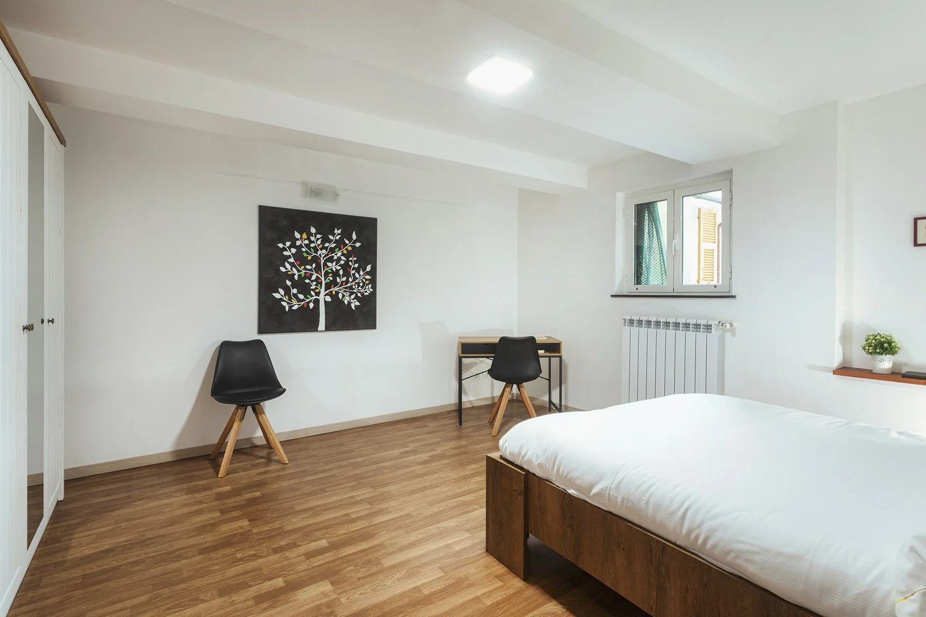 Un dormitorio luminoso con una cama de madera, un escritorio y arte en la pared.