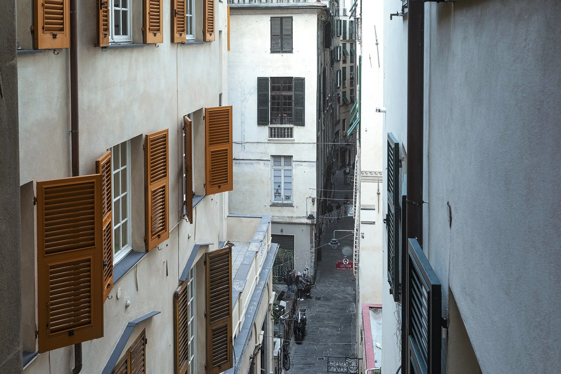 Un callejón urbano estrecho pasa entre edificios con ventanas con contraventanas.