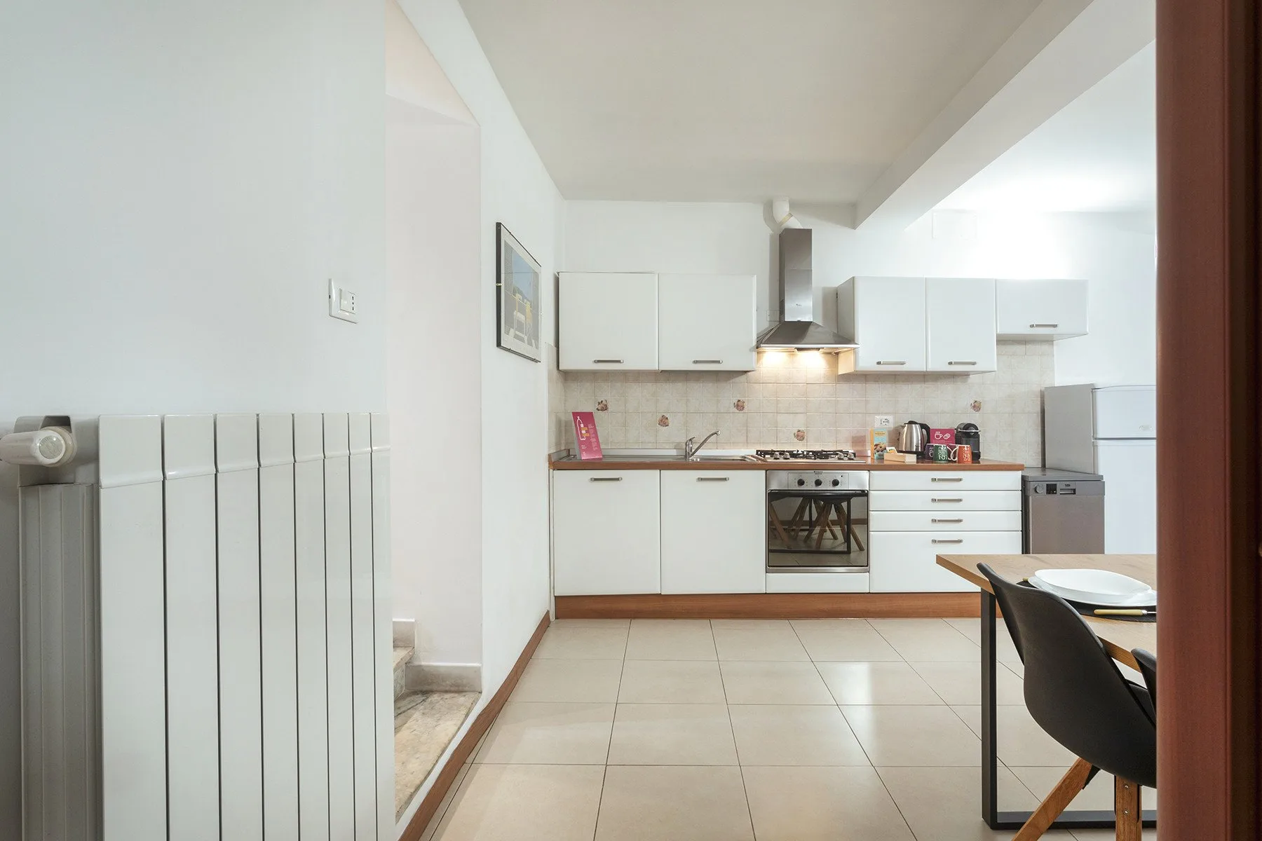 Una cocina luminosa con gabinetes blancos, un salpicadero de azulejos y una mesa de comedor.