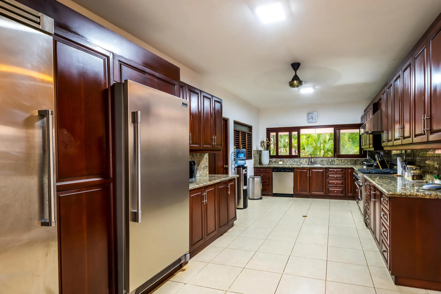 Una cocina amplia con gabinetes oscuros, electrodomésticos de acero inoxidable y piso de baldosas.
