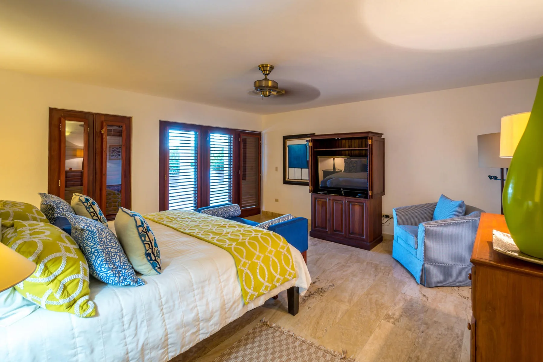 Un dormitorio con una cama grande, asientos y un mueble para televisión.
