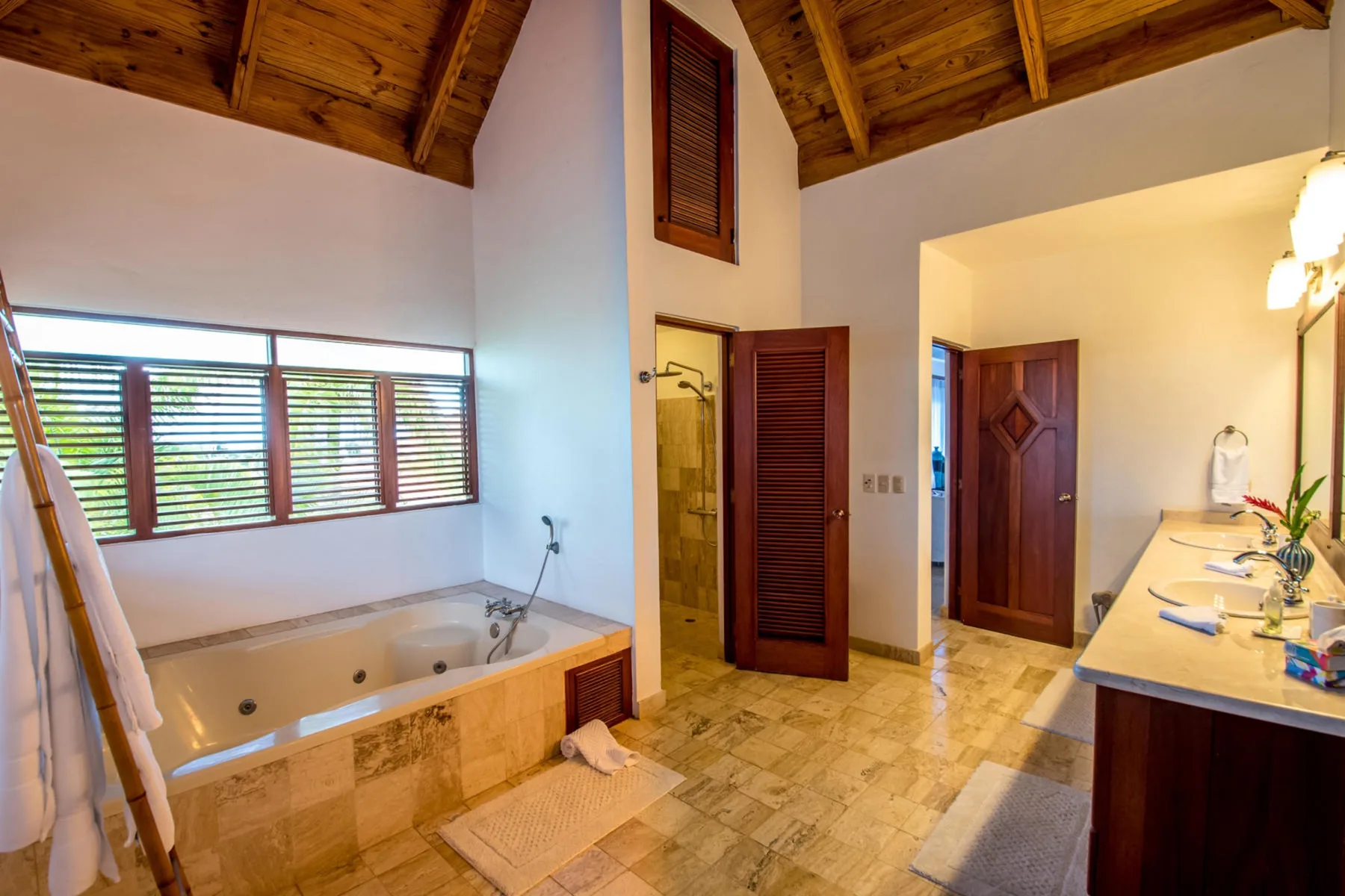 Un baño con bañera empotrada, ducha y techo revestido de madera.