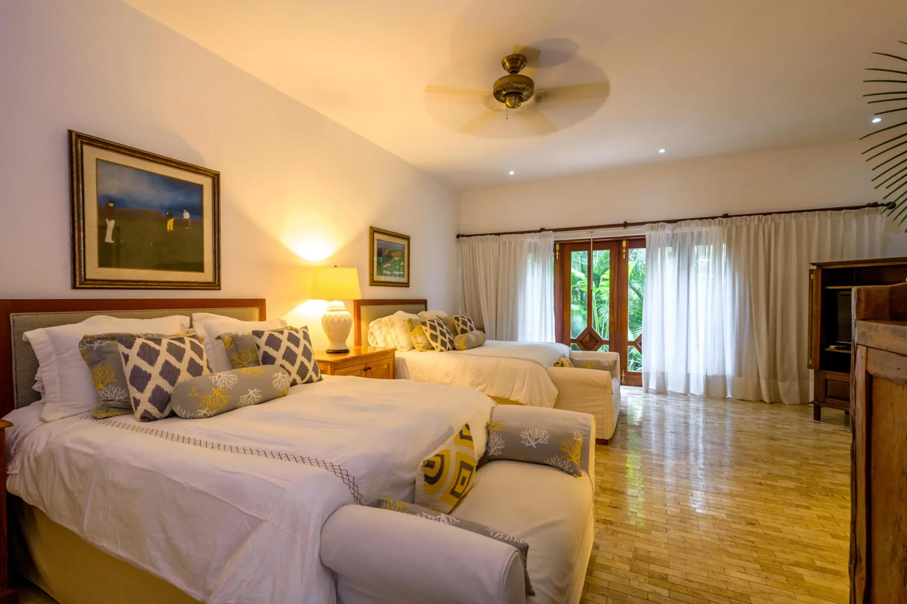 Un dormitorio con dos camas, una zona de estar y una ventana con vegetación al otro lado.