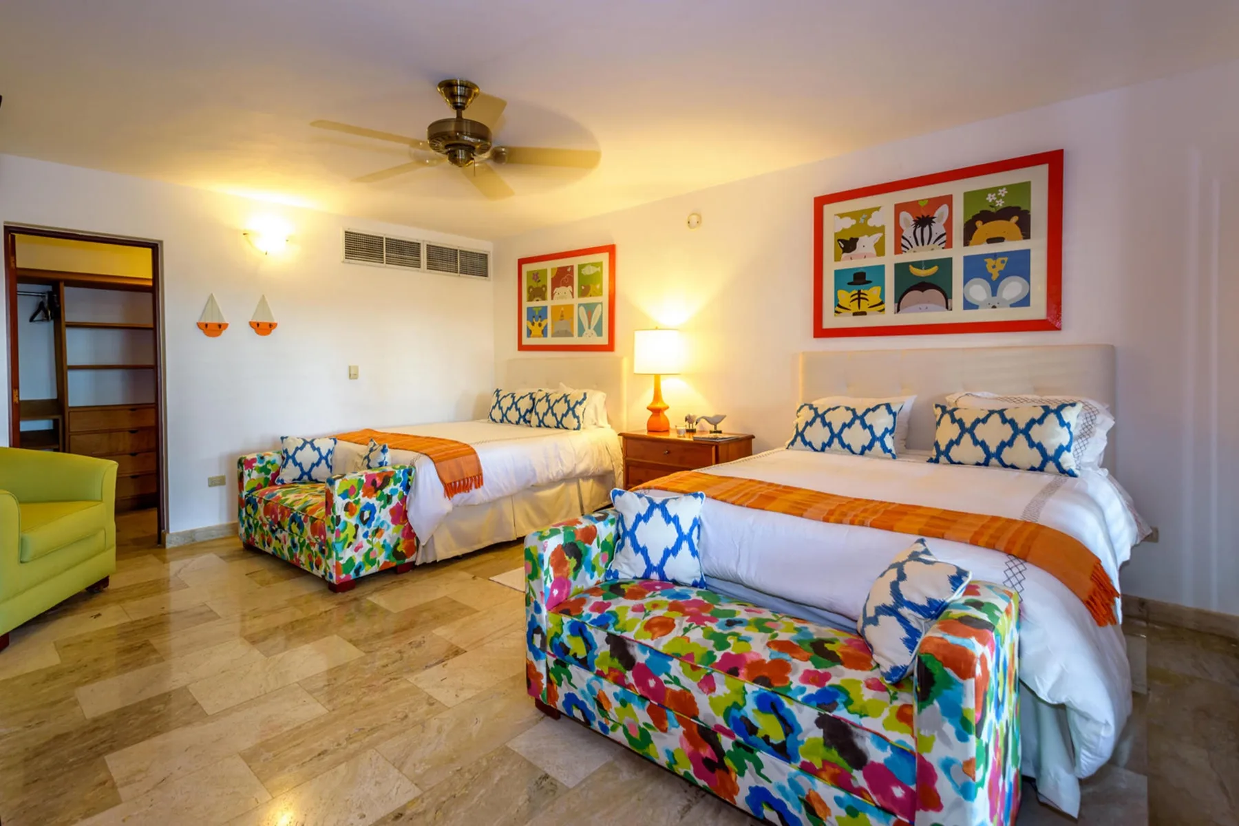 Un dormitorio colorido con dos camas y un banco estampado al pie de una de ellas.