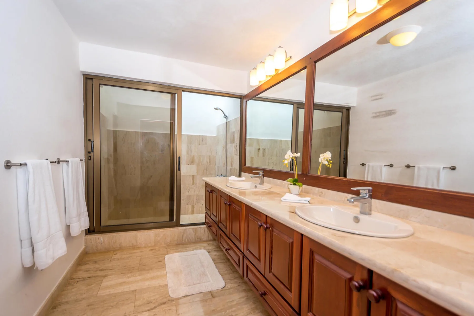 Un baño con un tocador largo, lavabos y armarios con espejo.