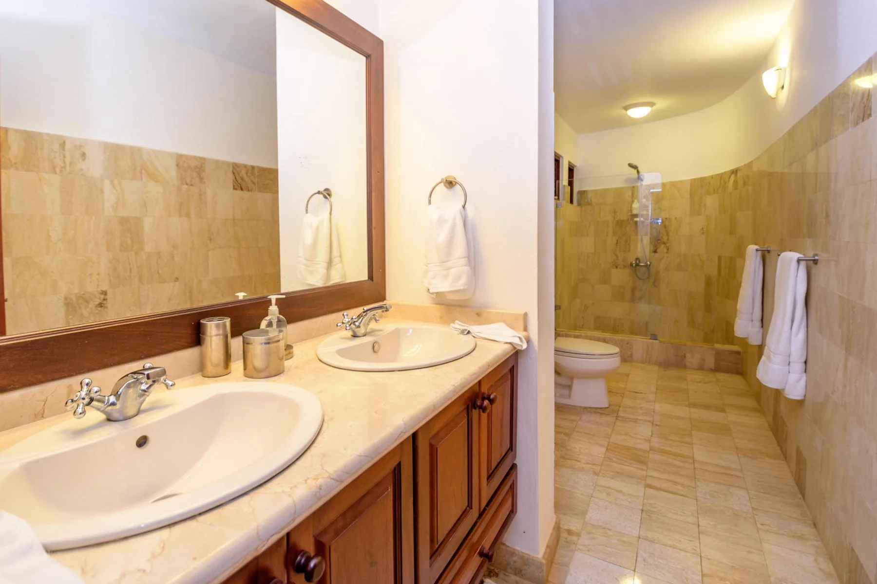 Un baño con un lavabo largo y una zona de ducha al fondo.