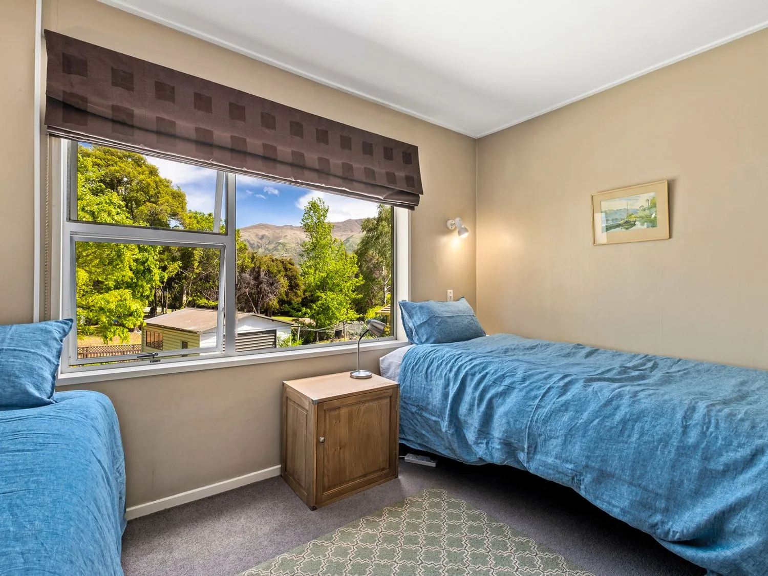 Un dormitorio con dos camas individuales y una ventana con vistas a los árboles y las montañas en Taha Wai - Wanaka Holiday Home, en Wanaka.