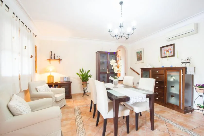 A bright dining room with a table, upholstered seating, and a wooden cabinet.