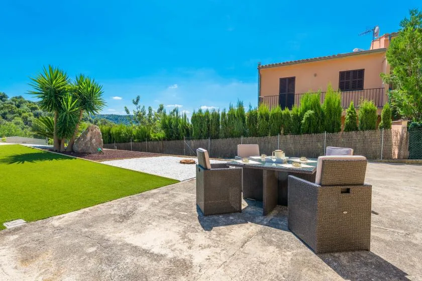 An outdoor dining area with a table and seating beside a green lawn.