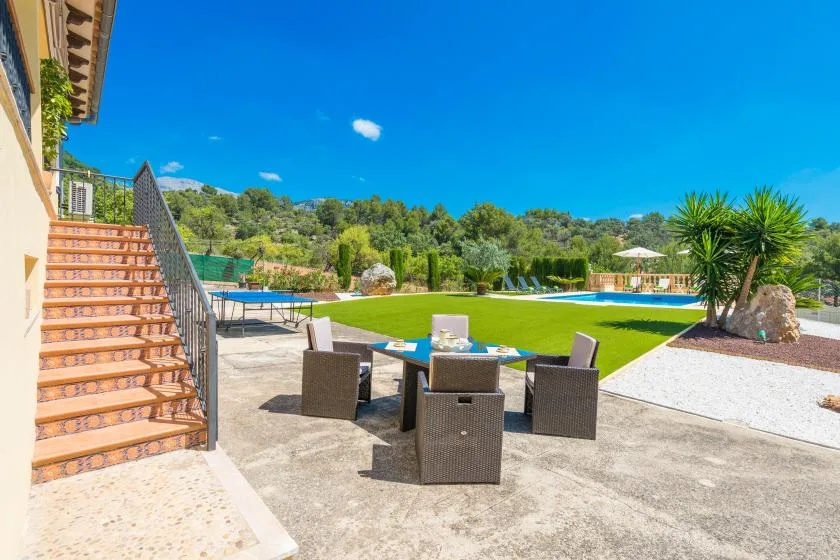 An outdoor pool area with patio seating and a landscaped lawn.