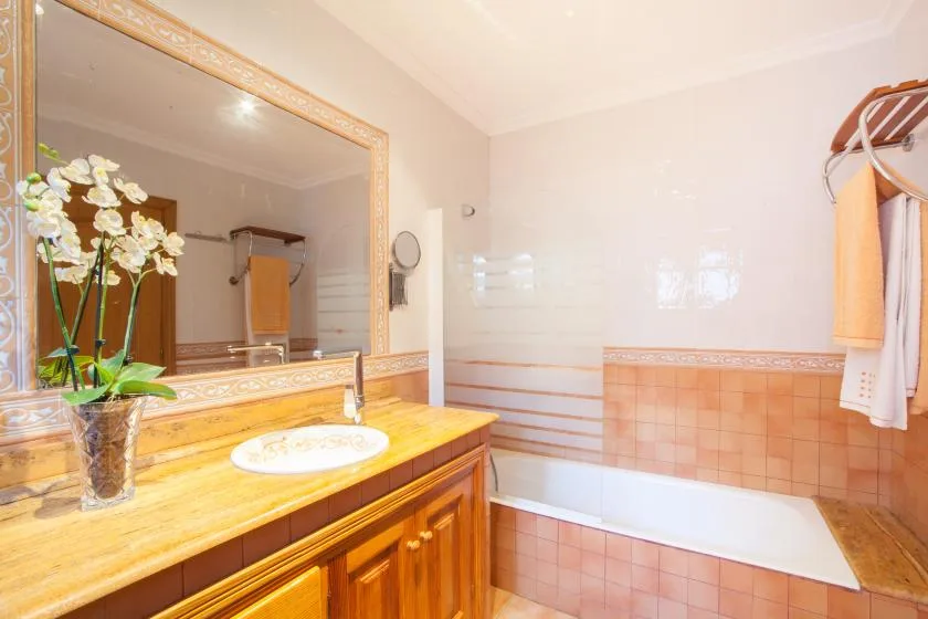 A bathroom with a wooden vanity, large mirror, and bathtub.