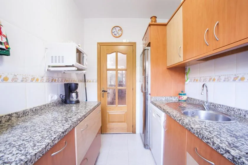 A bright kitchen with counters on both sides and a wooden door at the far end.