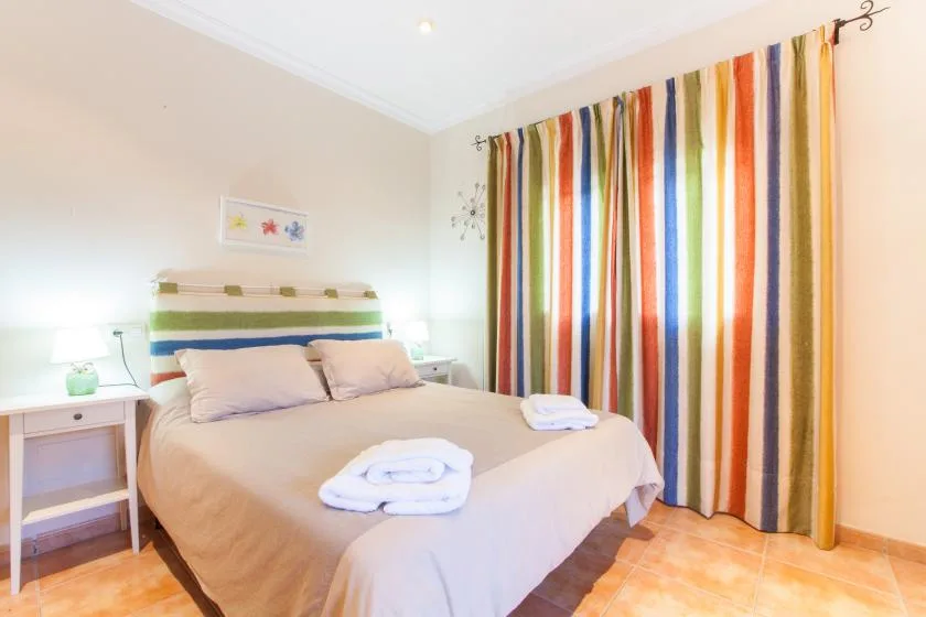 A bedroom with a bed and colorful striped curtains.