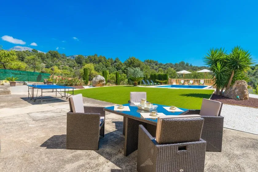 Outdoor dining seating overlooks a swimming pool and green lawn.