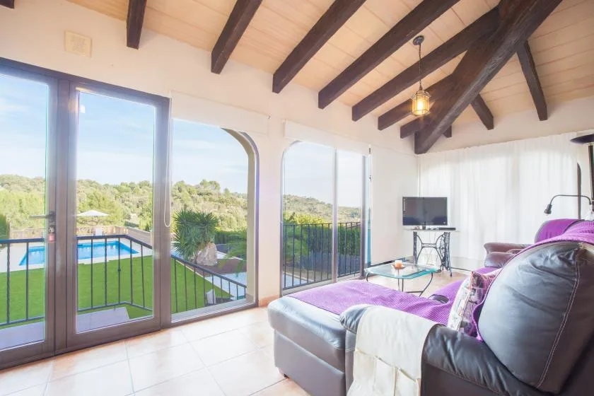 A bright living room with a large seating area beside glass doors opening to a terrace.