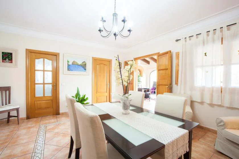 A bright dining room with a long table and light-colored seating.