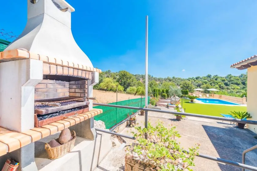 An outdoor barbecue area overlooks a swimming pool and landscaped grounds.