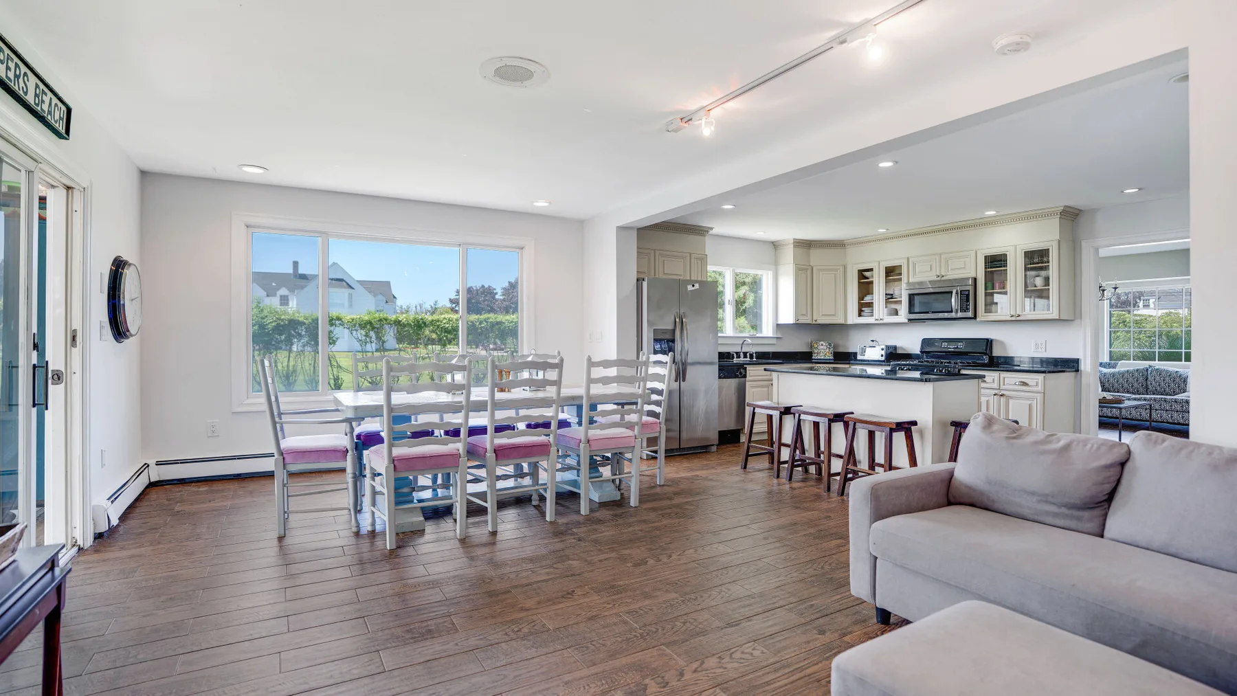 Una sala y comedor de concepto abierto con cocina y ventanas amplias.