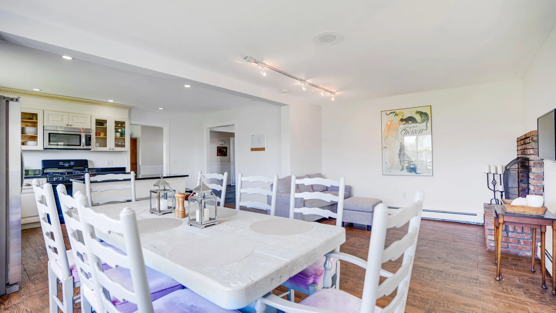 Un comedor abierto con una mesa blanca y la cocina al fondo.