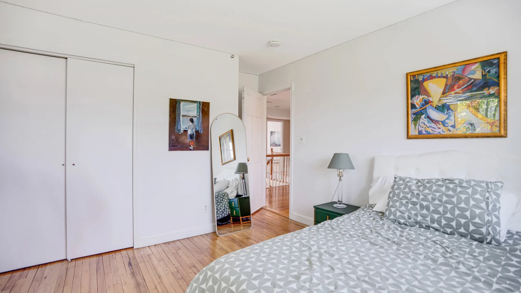 Un dormitorio luminoso con ropa de cama estampada y cuadros en las paredes.