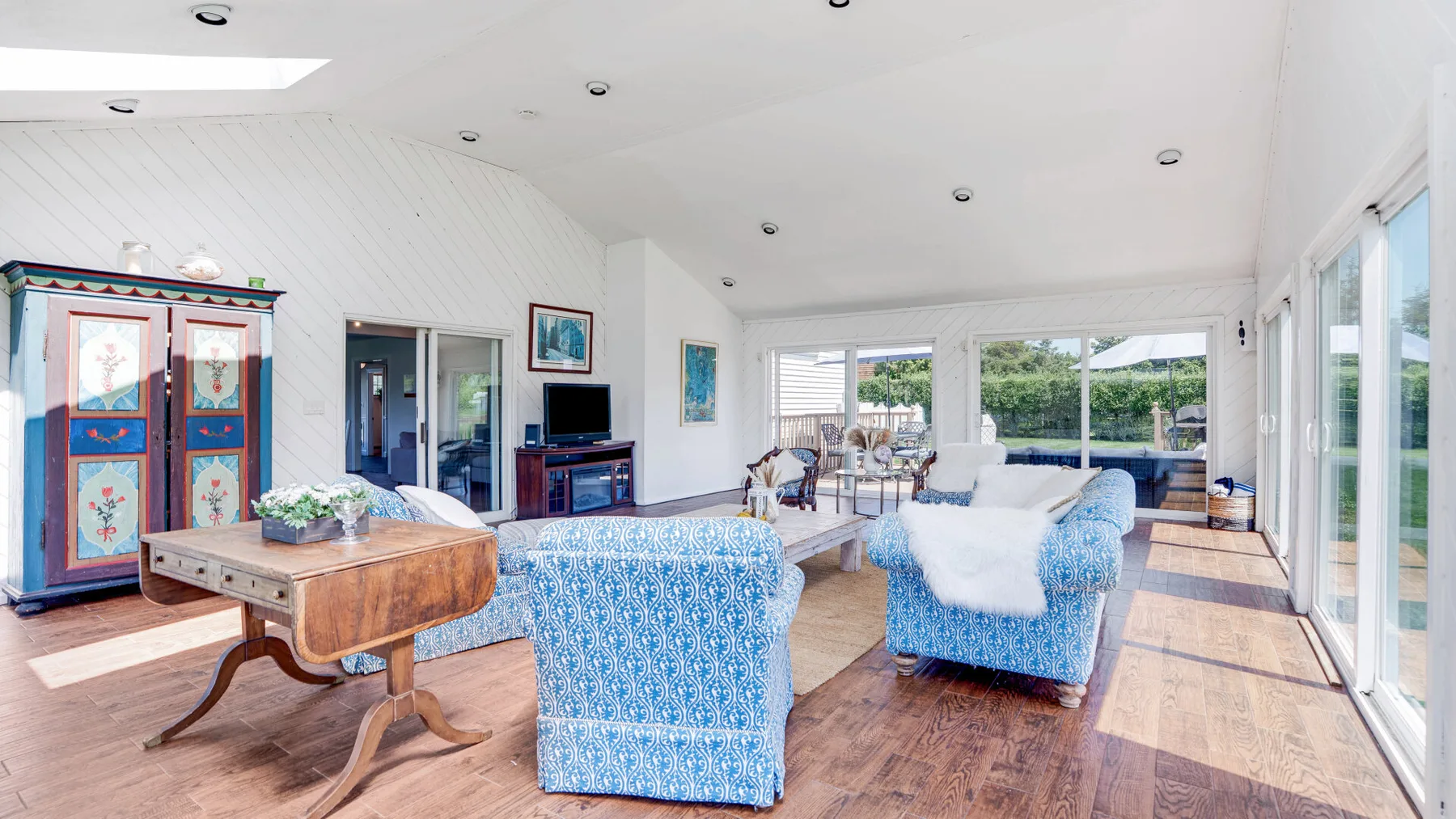 A bright living room with blue patterned seating and large windows.