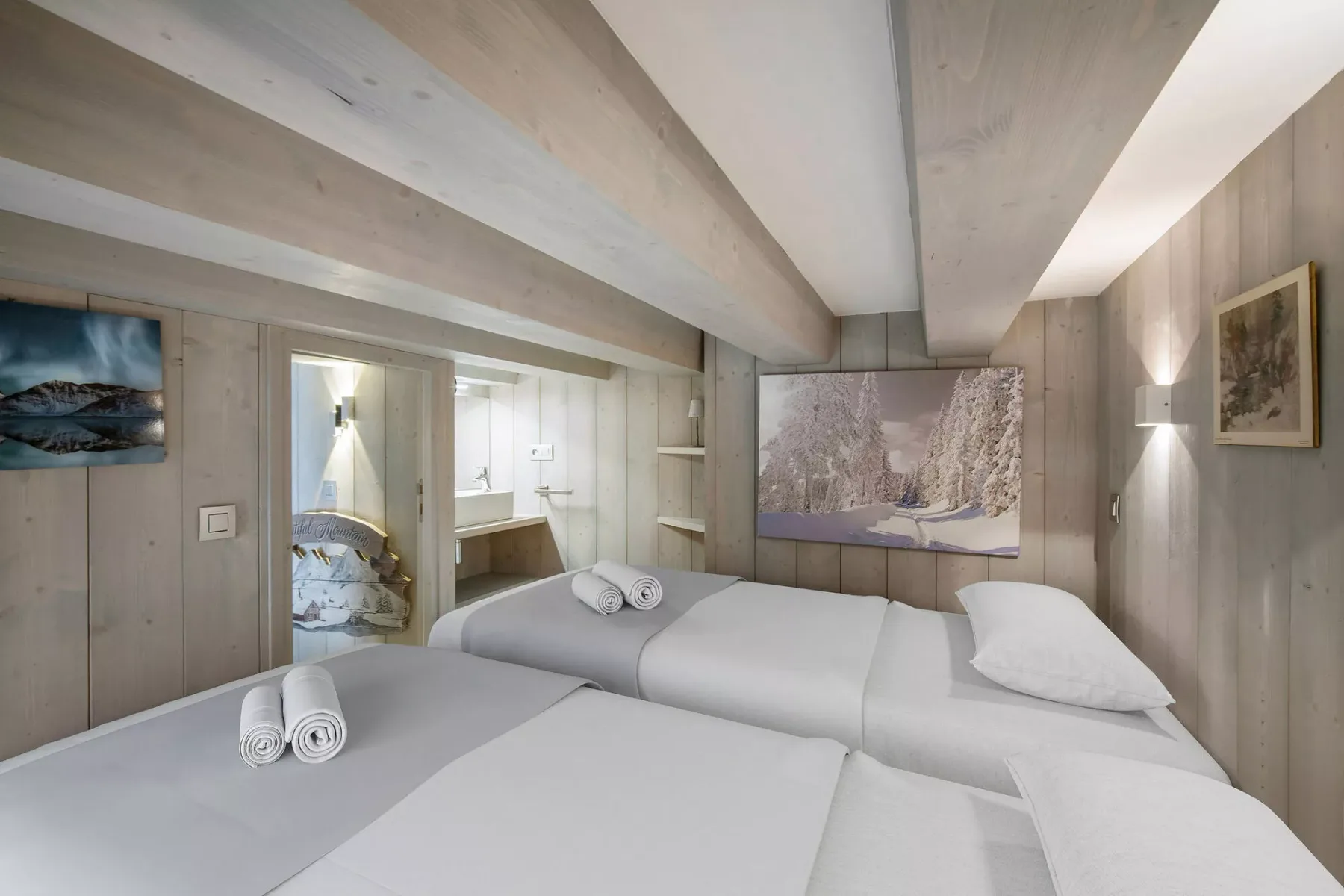 Un dormitorio luminoso con ropa de cama blanca y cuadros en las paredes.
