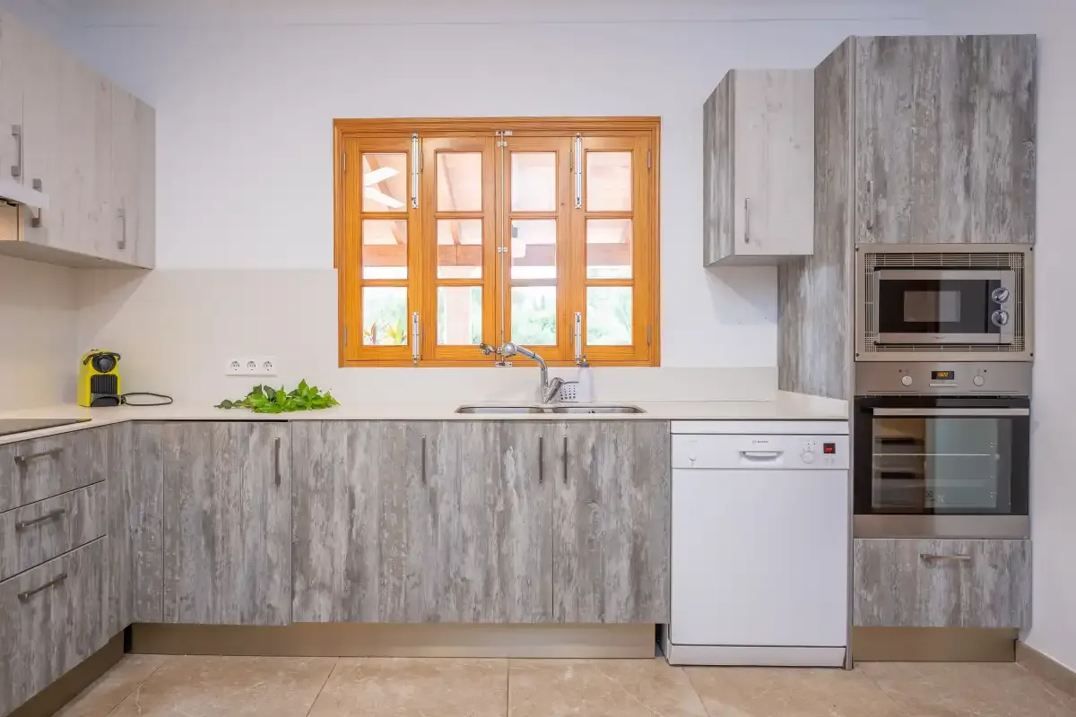 A kitchen with gray cabinets, a window, and built-in appliances.