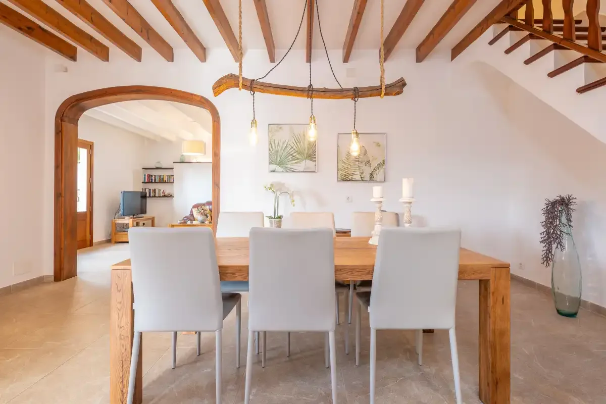 A dining area with a wooden table and seating beneath exposed ceiling beams.