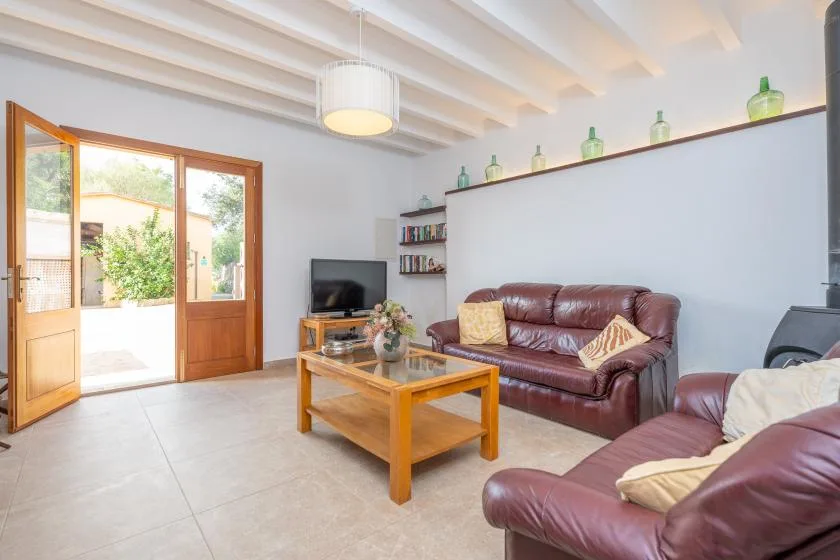 A bright living room with leather seating, a wooden coffee table, and an open door to the patio.