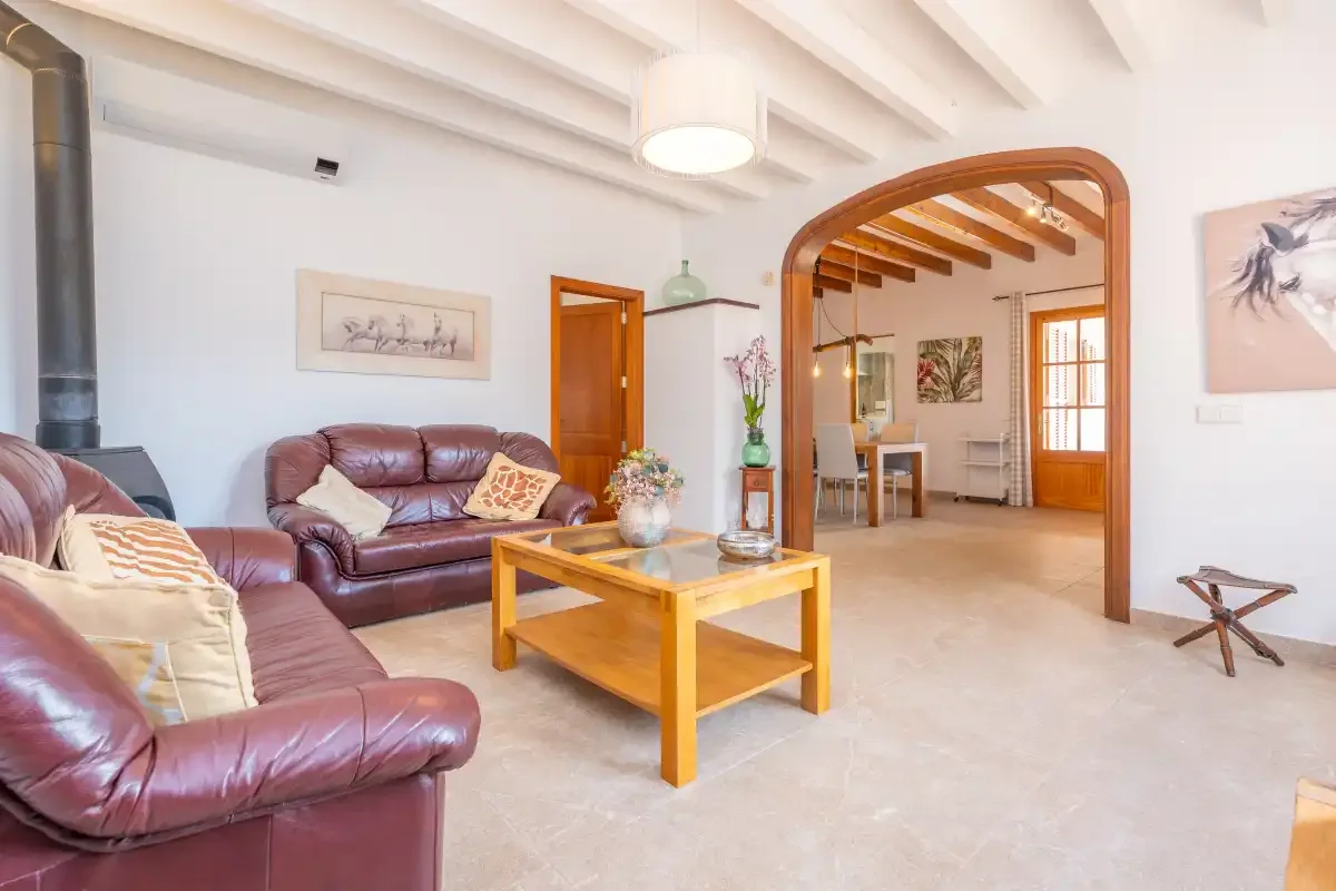 A living room with leather seating and a wooden coffee table opens into a dining area.