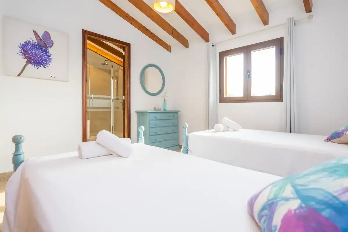 A bedroom with two beds, a turquoise dresser, and a window.