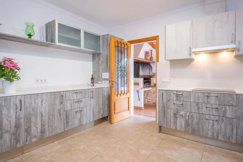 A bright kitchen with gray cabinets and an open wooden doorway.